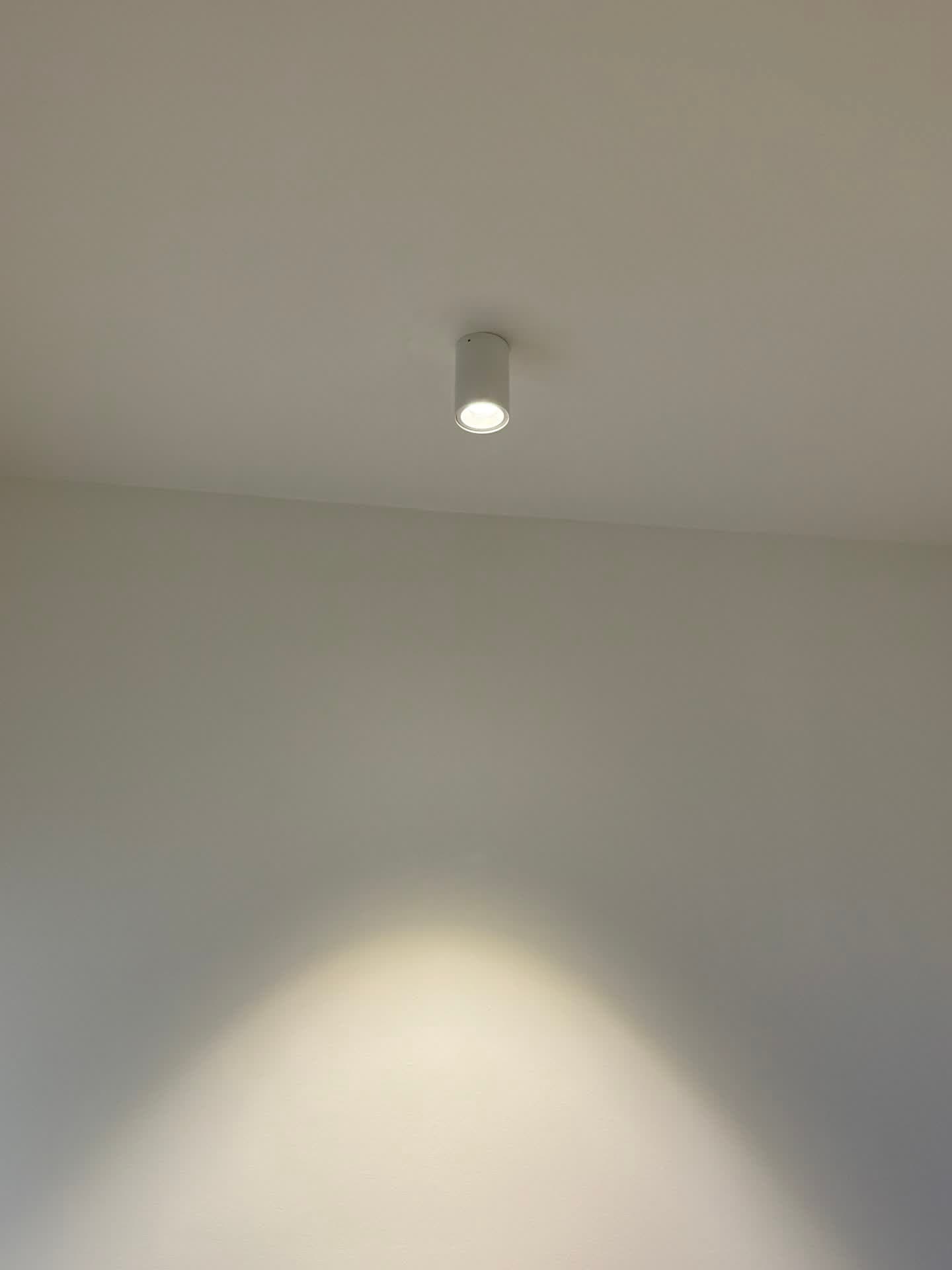 Close-up of a cylindrical LED wall-mounted downlight casting a directional beam in Harcourt Dental Clinic