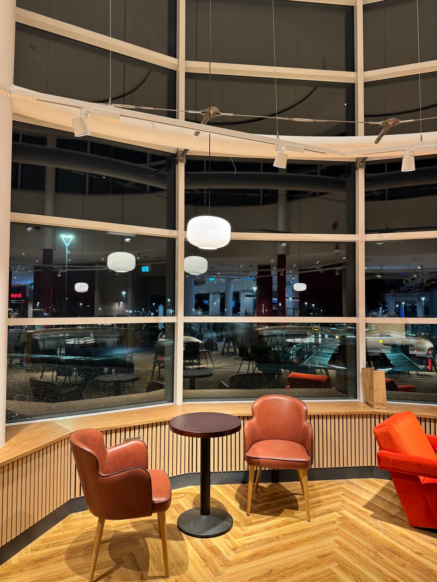 Window seating area with globe pendant lights reflecting in glass at night at Insomnia Liffey Valley