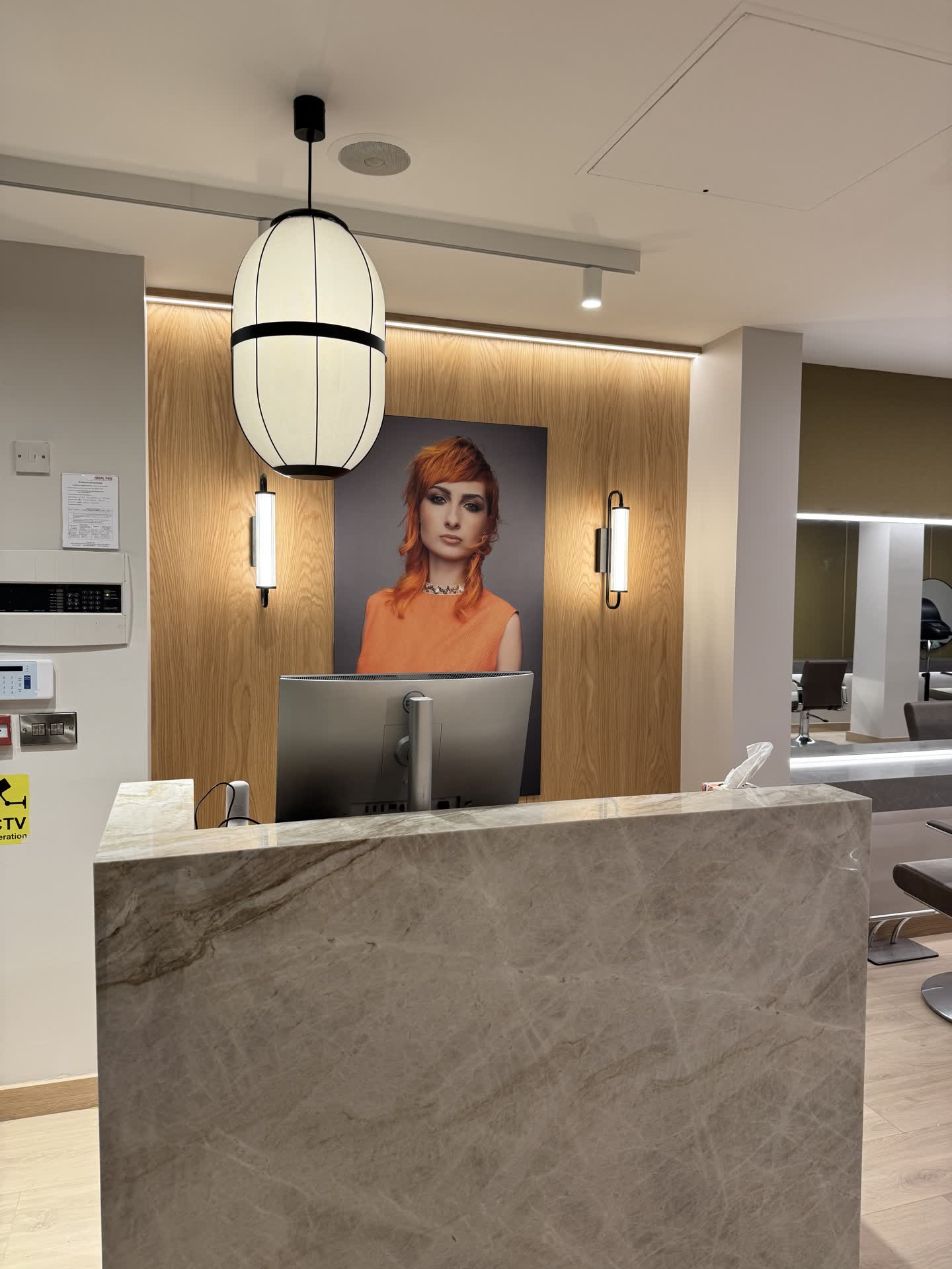 Zebra Hair Dressers reception desk with decorative pendant lamp and backlit product display wall